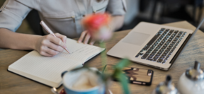 Personne prenant des notes devant un ordinateur lors d'un webinaire sur la santé mentale. 