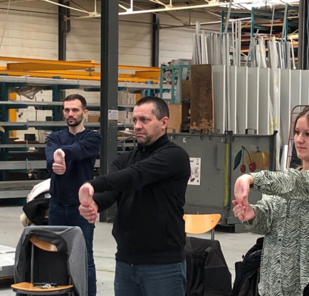 Des personnes en atelier réalisant un étirement des poignets.