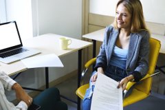 Femme cadre en entretien de recrutement dans un bureau face à un candidat, utilisant un ordinateur portable
